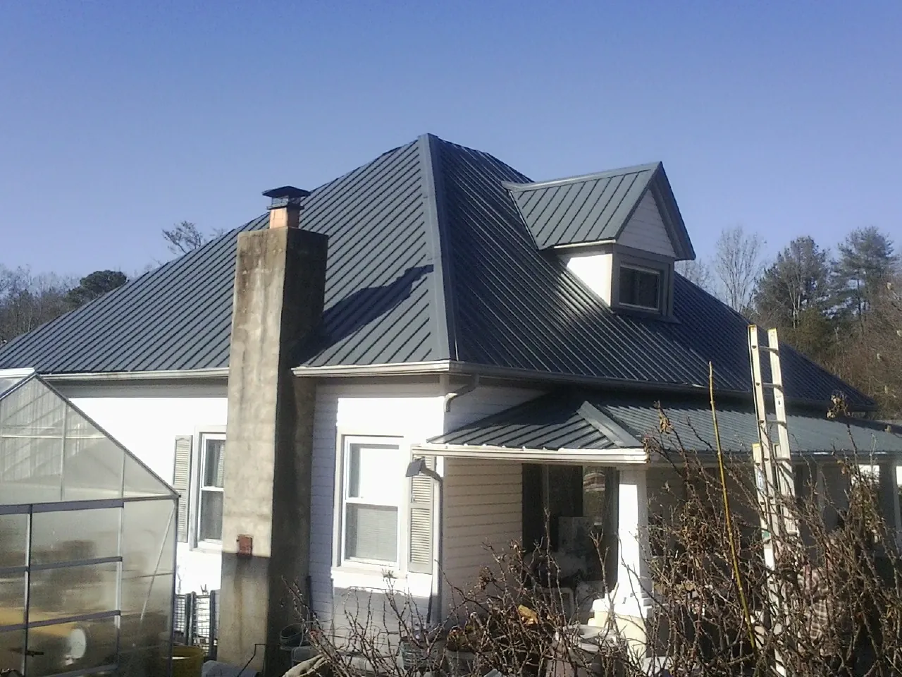 Dark blue standing seam metal roof on a white farmhouse with dormer — Slate & Tile Roof Repair by Roofing Brothers in Steubenville