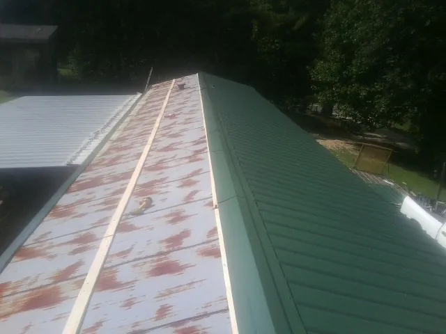 Old rusted panels beside newly installed green metal roofing — Wind Damage Roof Repair by Roofing Brothers in Steubenville