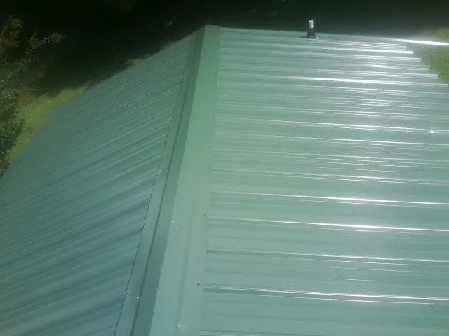 New green metal panels meeting at the ridge of a roof — Flat Roof Repair work by our crew in Steubenville
