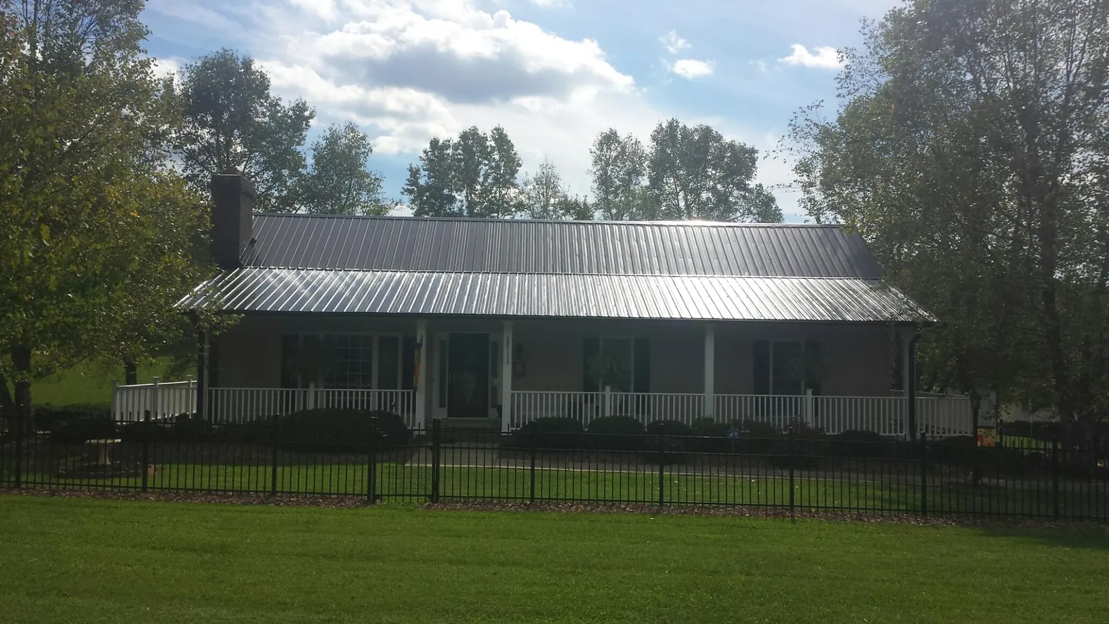 Gray metal roof on a brick ranch with a full width front porch — Gutter Guard Installation work by our crew in Steubenville