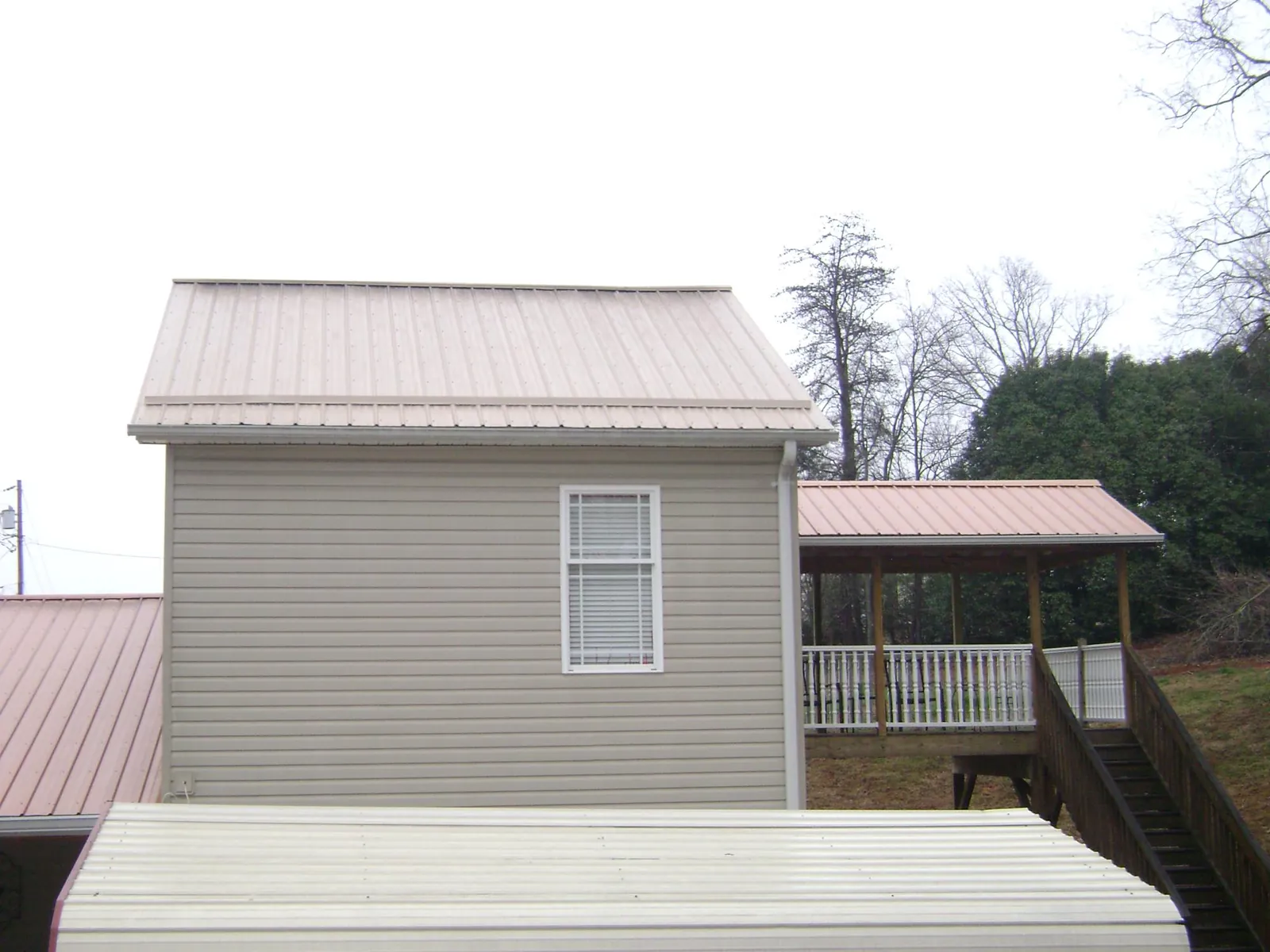 Tan metal roofs on a two story addition and attached porch, from a Roof Replacement job in Steubenville