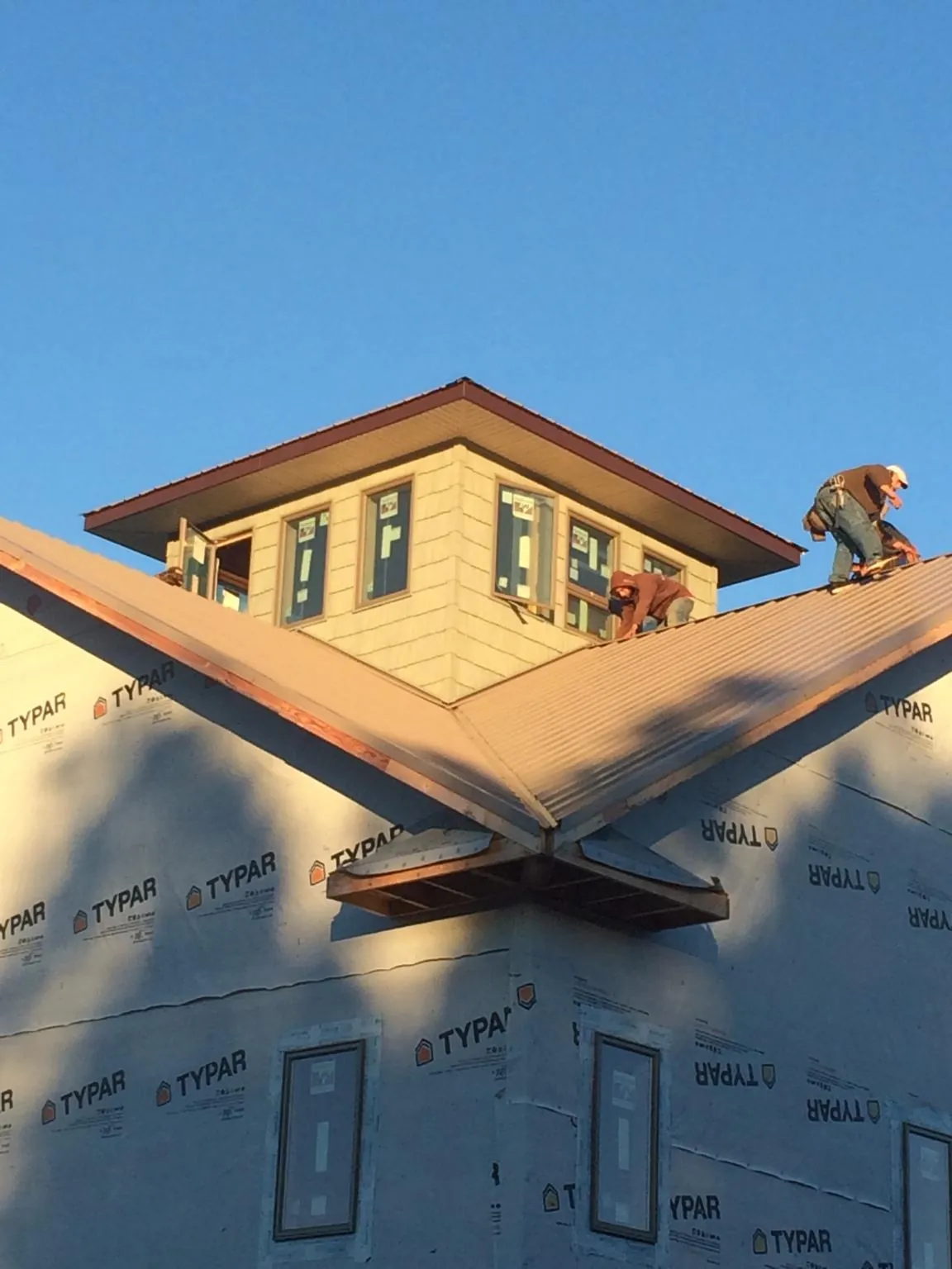 Roofers working around a rooftop cupola on a new metal roof at sunset — Roof Waterproofing in Steubenville by Roofing Brothers